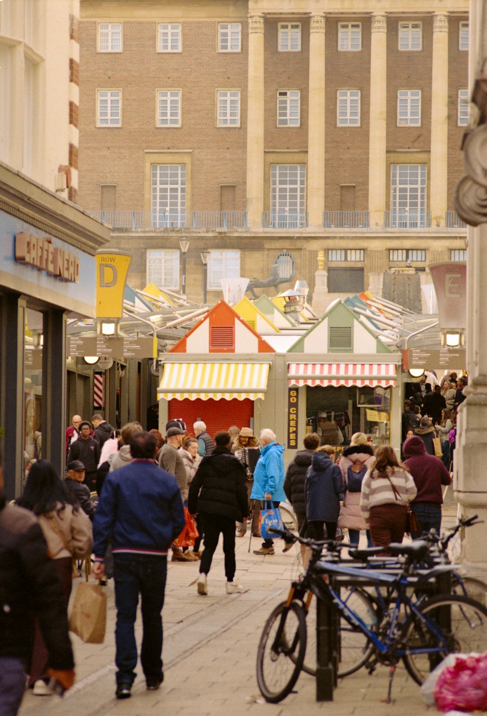 People browse a bustling street market with colorful stalls.