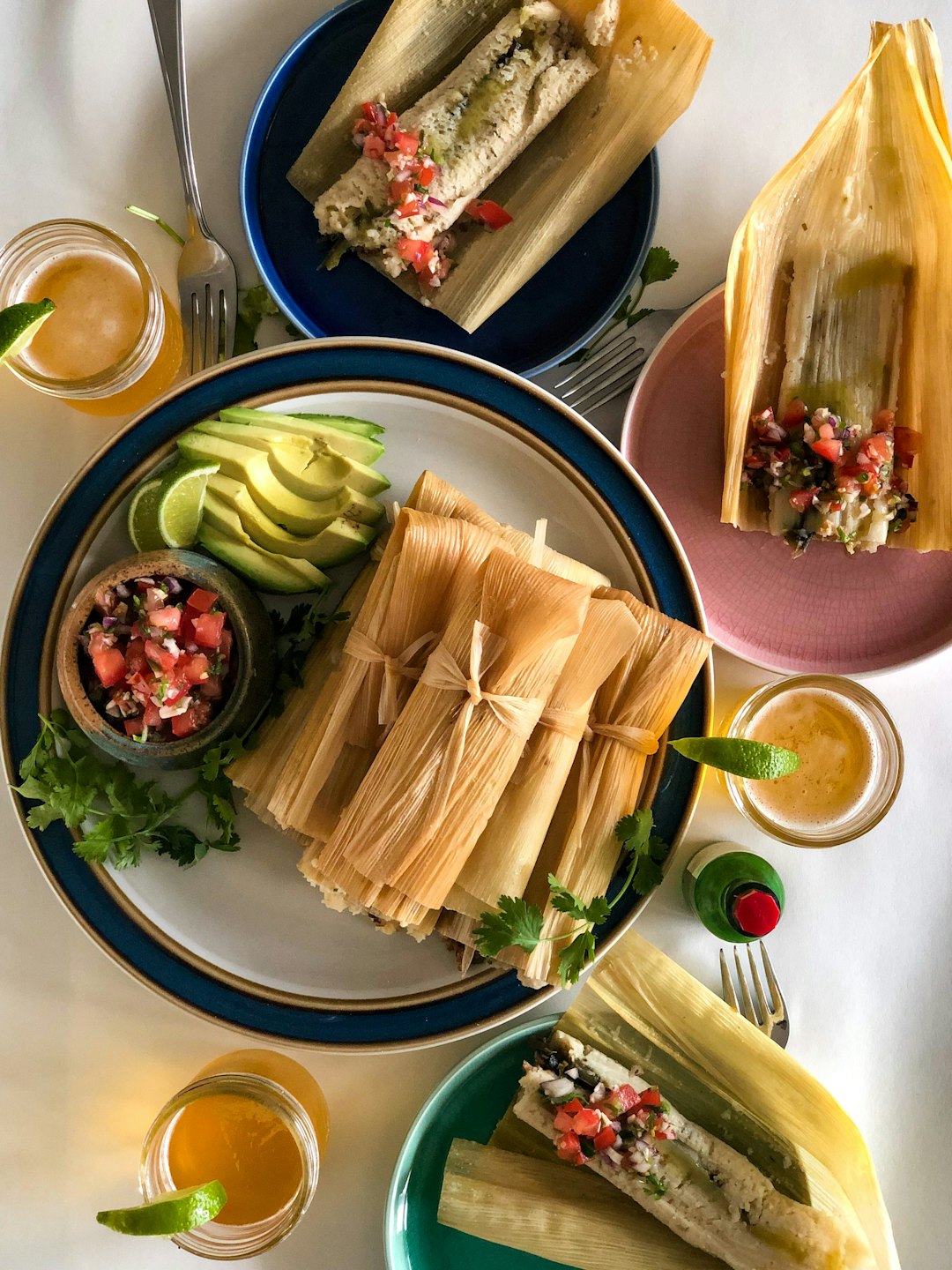 Unwrapped tamales with salsa and sides served on a table.