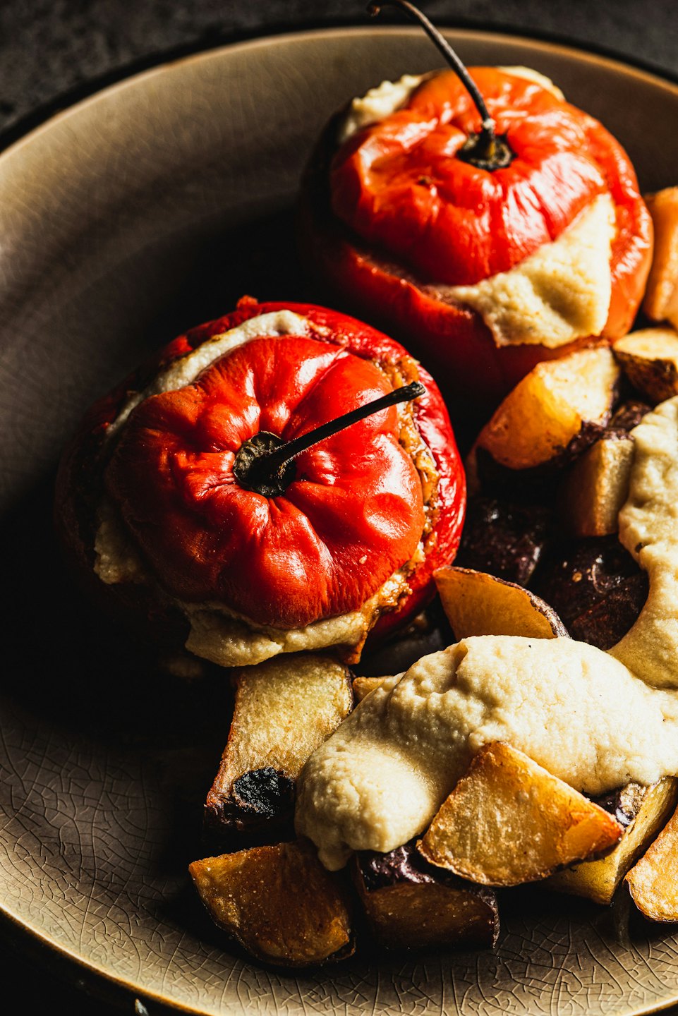 Two stuffed red peppers served with roasted potato wedges.