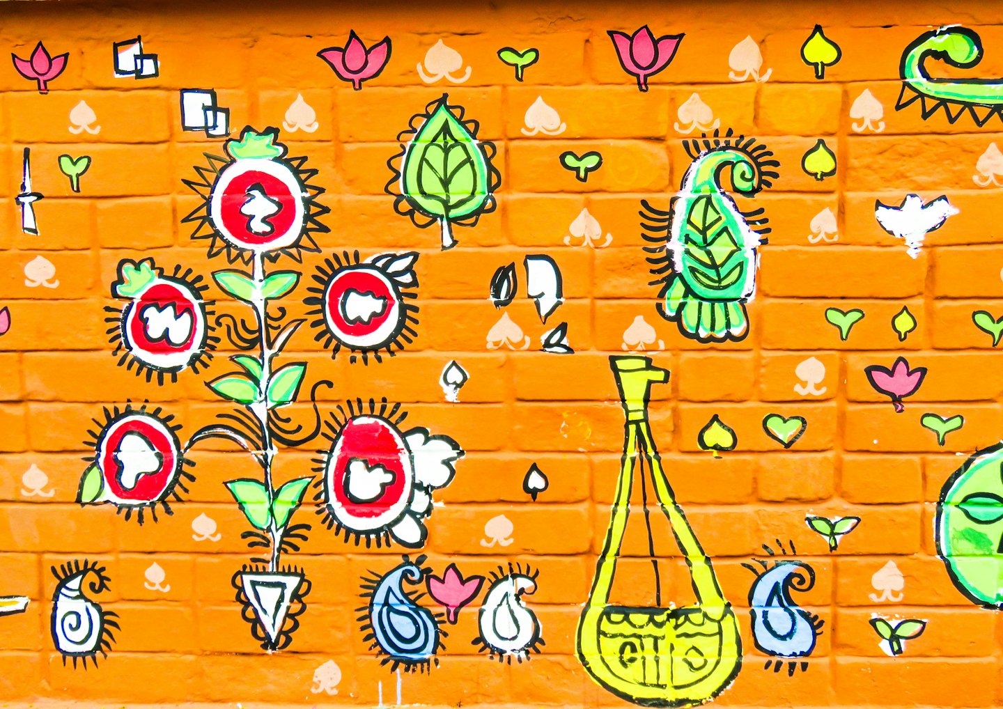 Colorful abstract folk art painted on an orange brick wall.